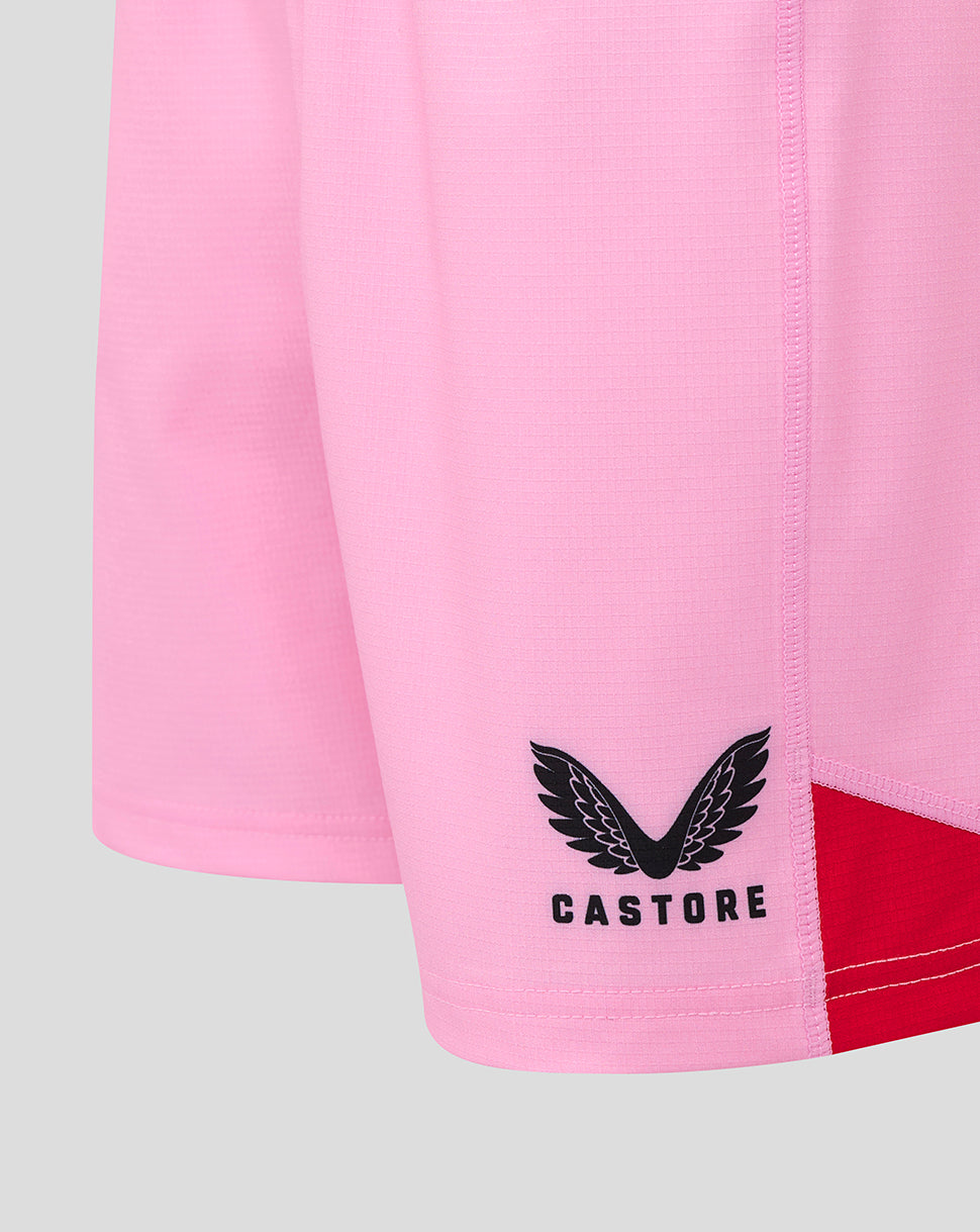 Close-up of pink shorts featuring the Castore logo near the hem and a red side panel