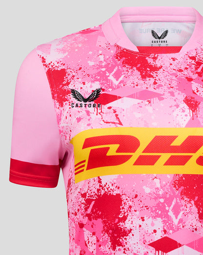 Close up of front pink Harlequins away replica shirt showing the club crest and bold DHL band over a splatter design