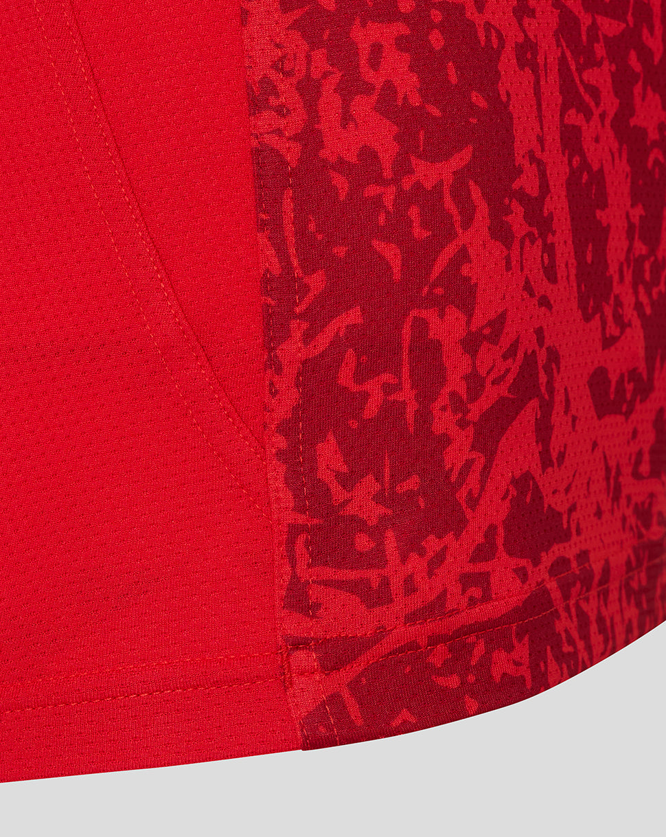 Close-up of the curved hem and side panel of the red Saracens tee with a textured abstract pattern.