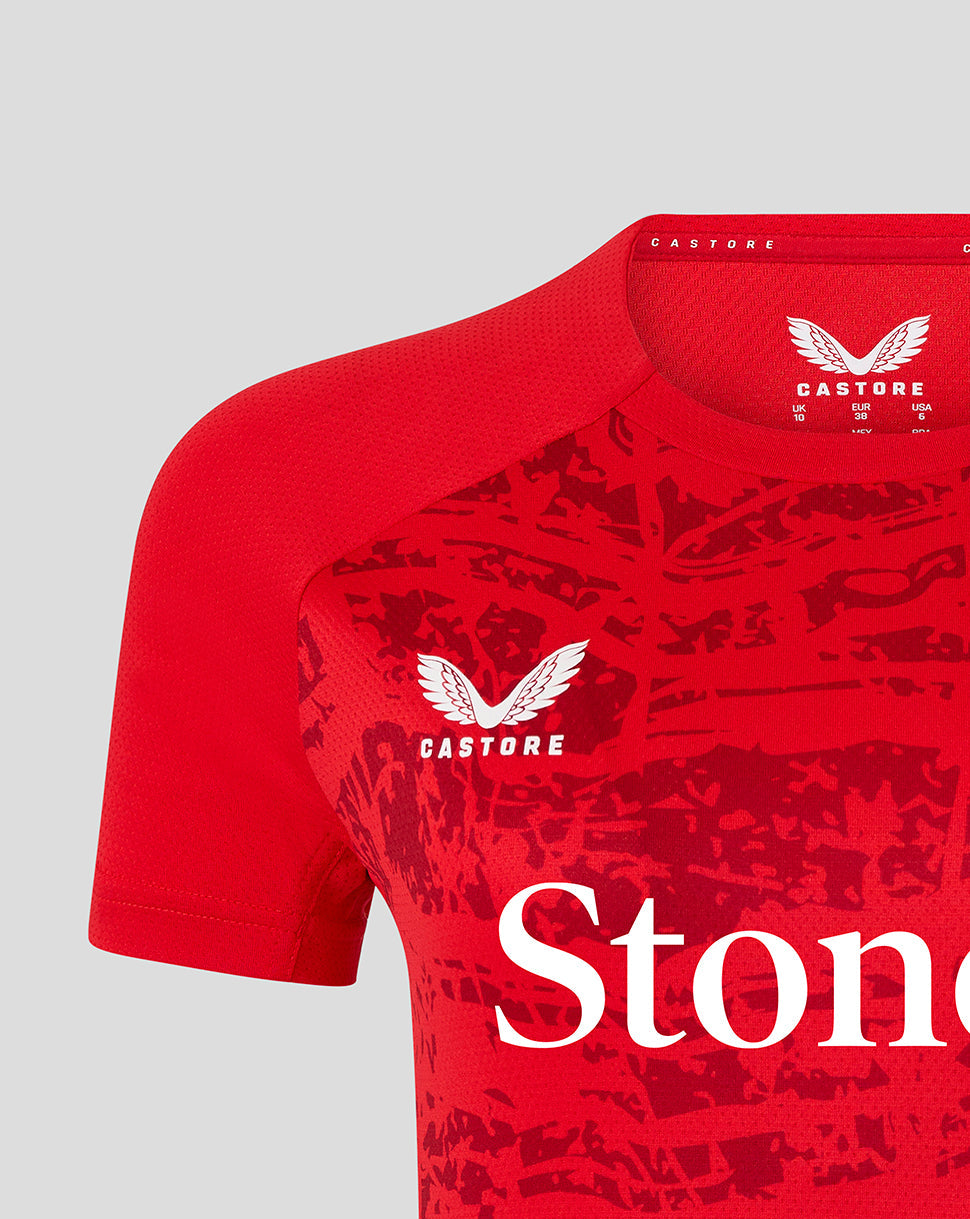 Close-up of red Saracens tee showing Castore branding at the collar and a white winged crest on the chest with partial StoneX lettering.