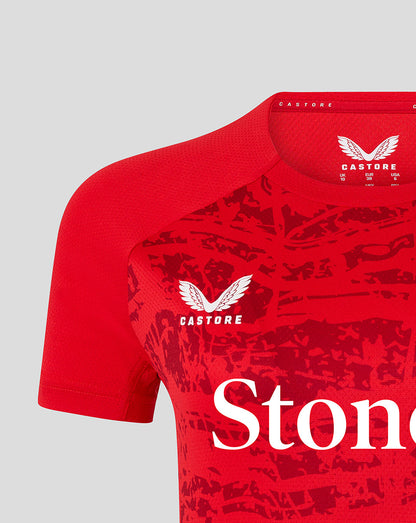 Close-up of red Saracens tee showing Castore branding at the collar and a white winged crest on the chest with partial StoneX lettering.