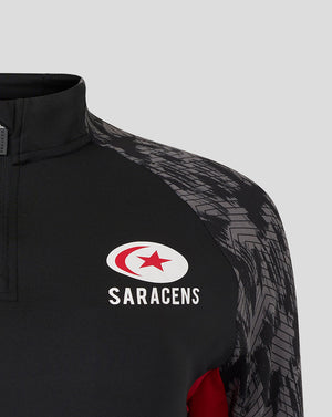 Close-up of black Saracens midlayer with a quarter-zip collar, chest logos and grey patterned sleeves.