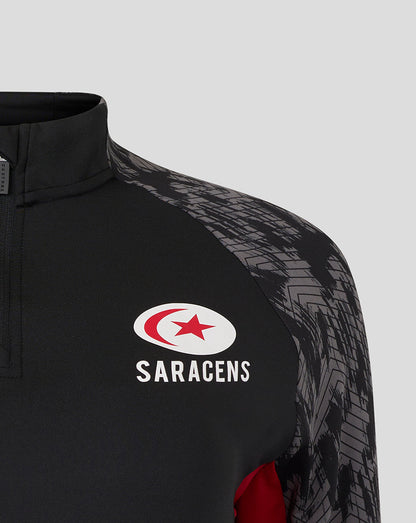 Close-up of black Saracens midlayer with a quarter-zip collar, chest logos and grey patterned sleeves.