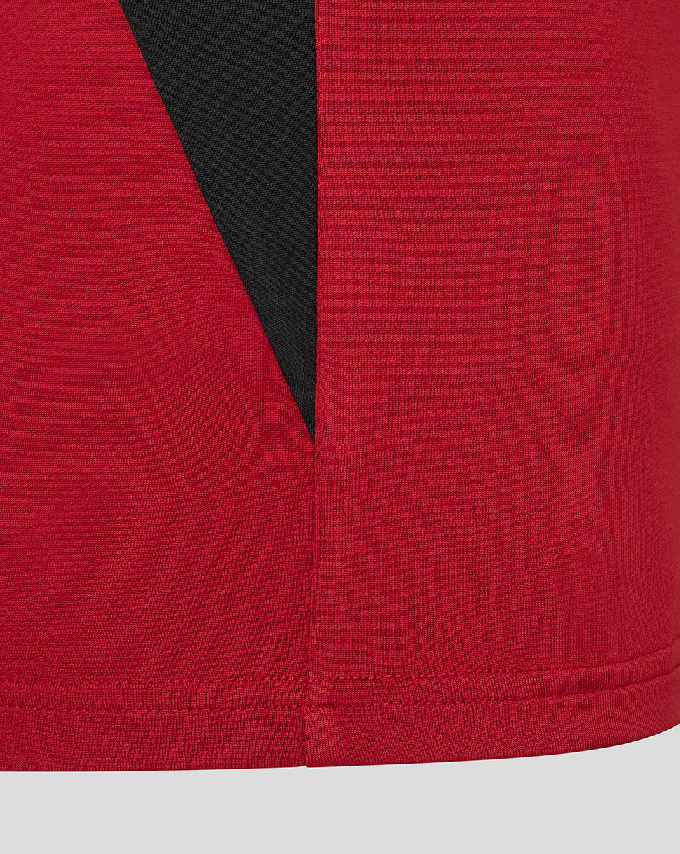 Hem detail of red training top showing a black side panel and neat stitching