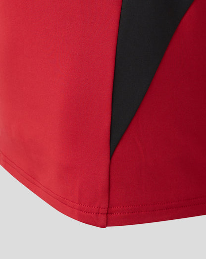 Front close-up of red Saracens training drill top showing a bold black diagonal side panel.