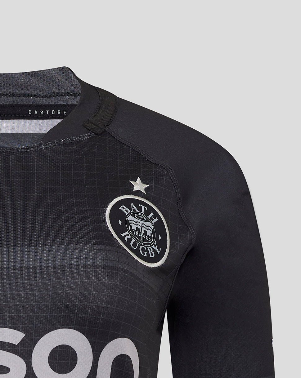 Close up of Bath Rugby crest on black replica shirt with grid texture and Castore label visible at collar