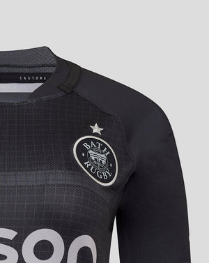 Close up of Bath Rugby crest on black replica shirt with grid texture and Castore label visible at collar