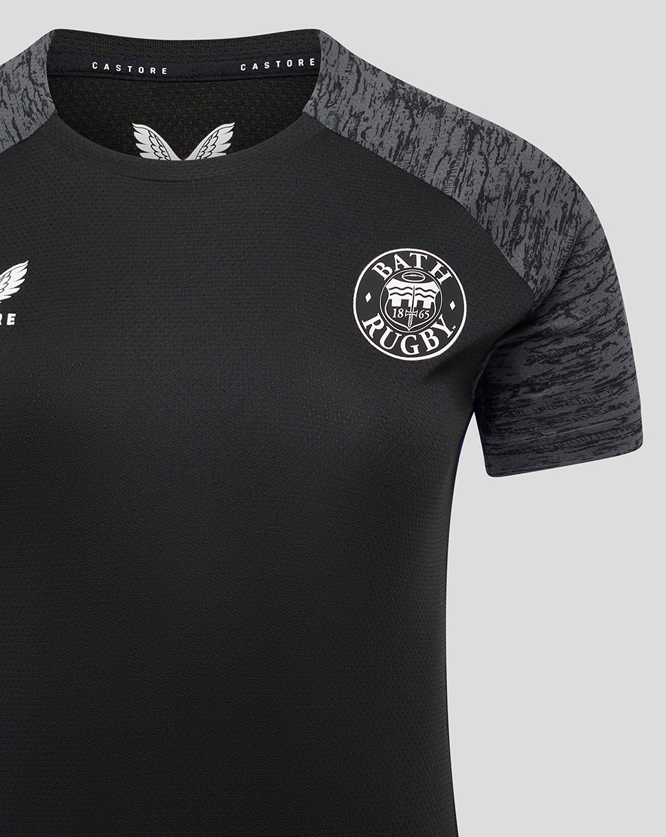 Close-up of Bath Rugby training tee front showing crest on left chest and textured fabric with grey shoulder panels