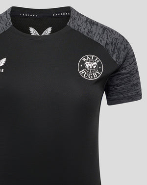Close-up of Bath Rugby training tee front showing crest on left chest and textured fabric with grey shoulder panels