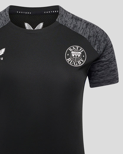 Close-up of Bath Rugby training tee front showing crest on left chest and textured fabric with grey shoulder panels