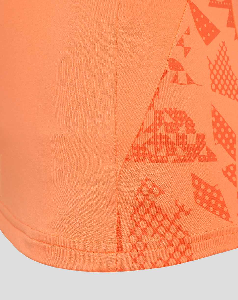 Close up of curved hem and side panel graphic on the orange England Rugby women's performance midlayer.