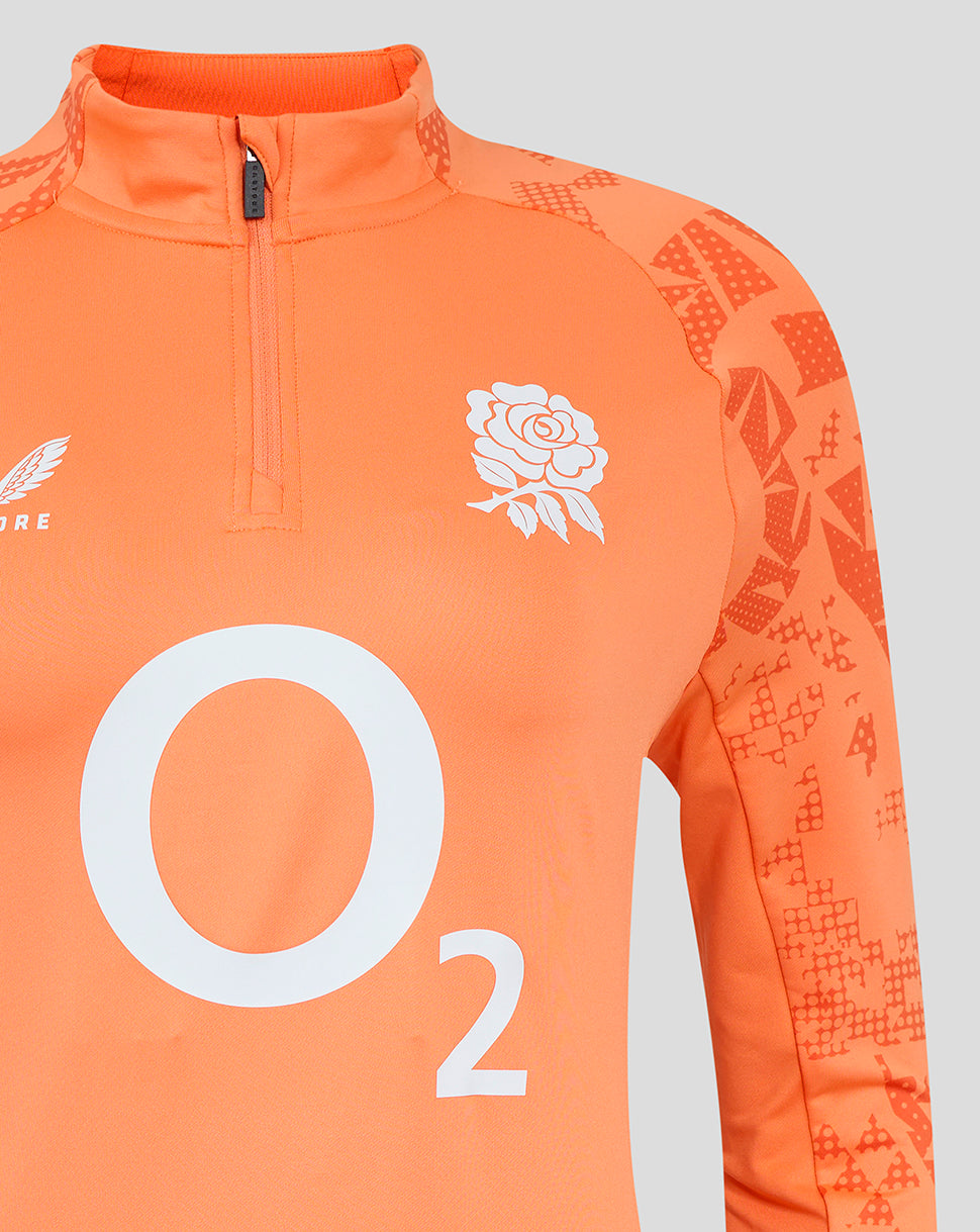 Close up of the orange England Rugby Women's Performance midlayer top featuring a rose crest on the chest and a large O2 graphic across the front, with patterned sleeves.