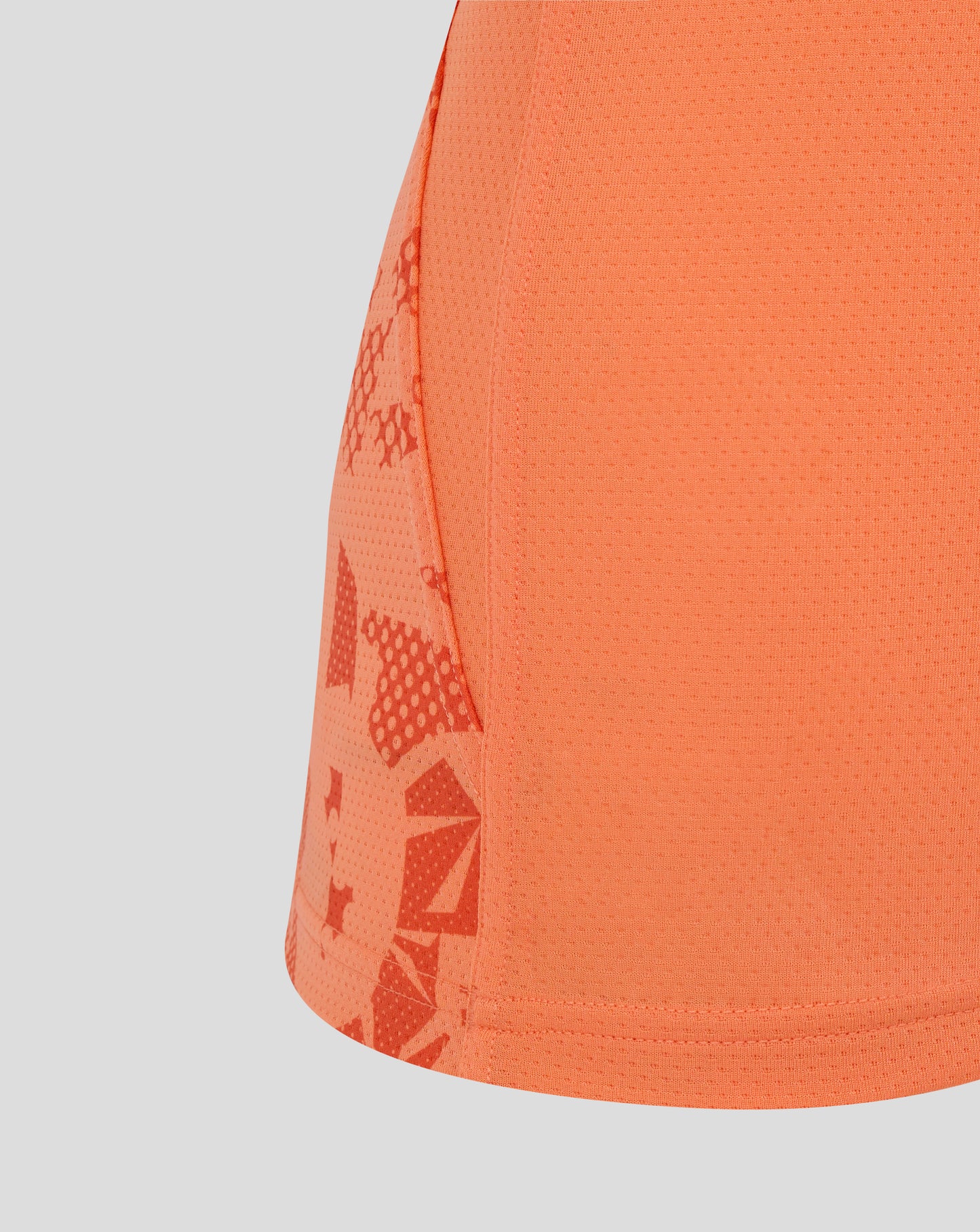 Close-up of melon colored England Rugby women's performance sleeveless top showing dotted fabric and abstract side panel print.
