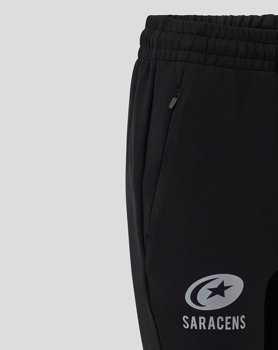 Close-up of black women's travel knit pants showing a zippered side pocket and Saracens logo on the leg