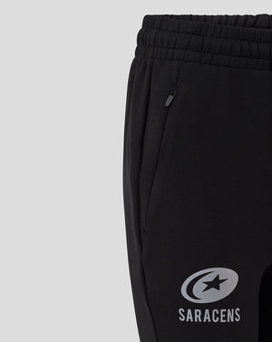 Close-up of black women's travel knit pants showing a zippered side pocket and Saracens logo on the leg