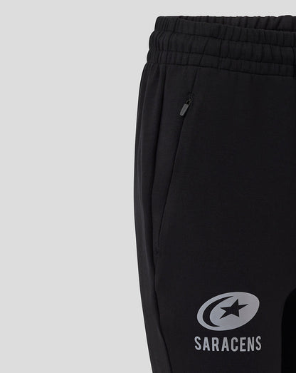 Close-up of black women's travel knit pants showing a zippered side pocket and Saracens logo on the leg