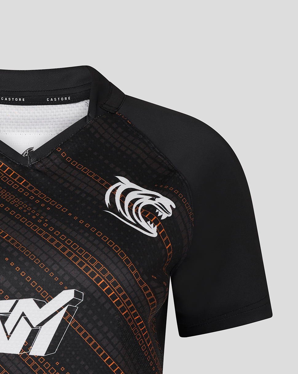 Detail of the front right chest with a large white sponsor logo and diagonal orange pattern on black fabric.