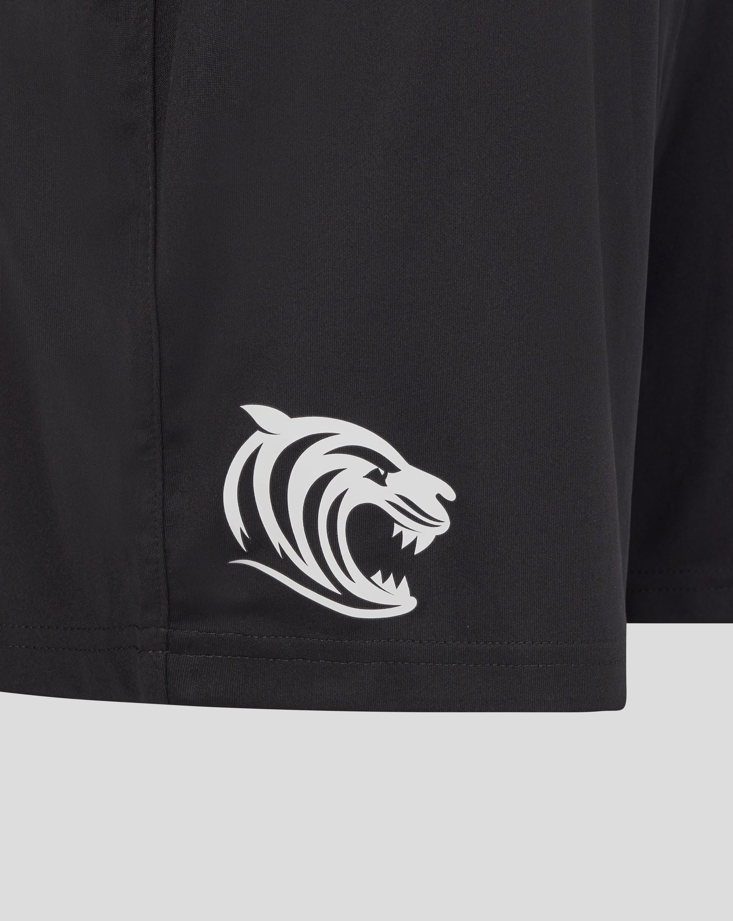 Close up of black training shorts fabric with a white tiger emblem
