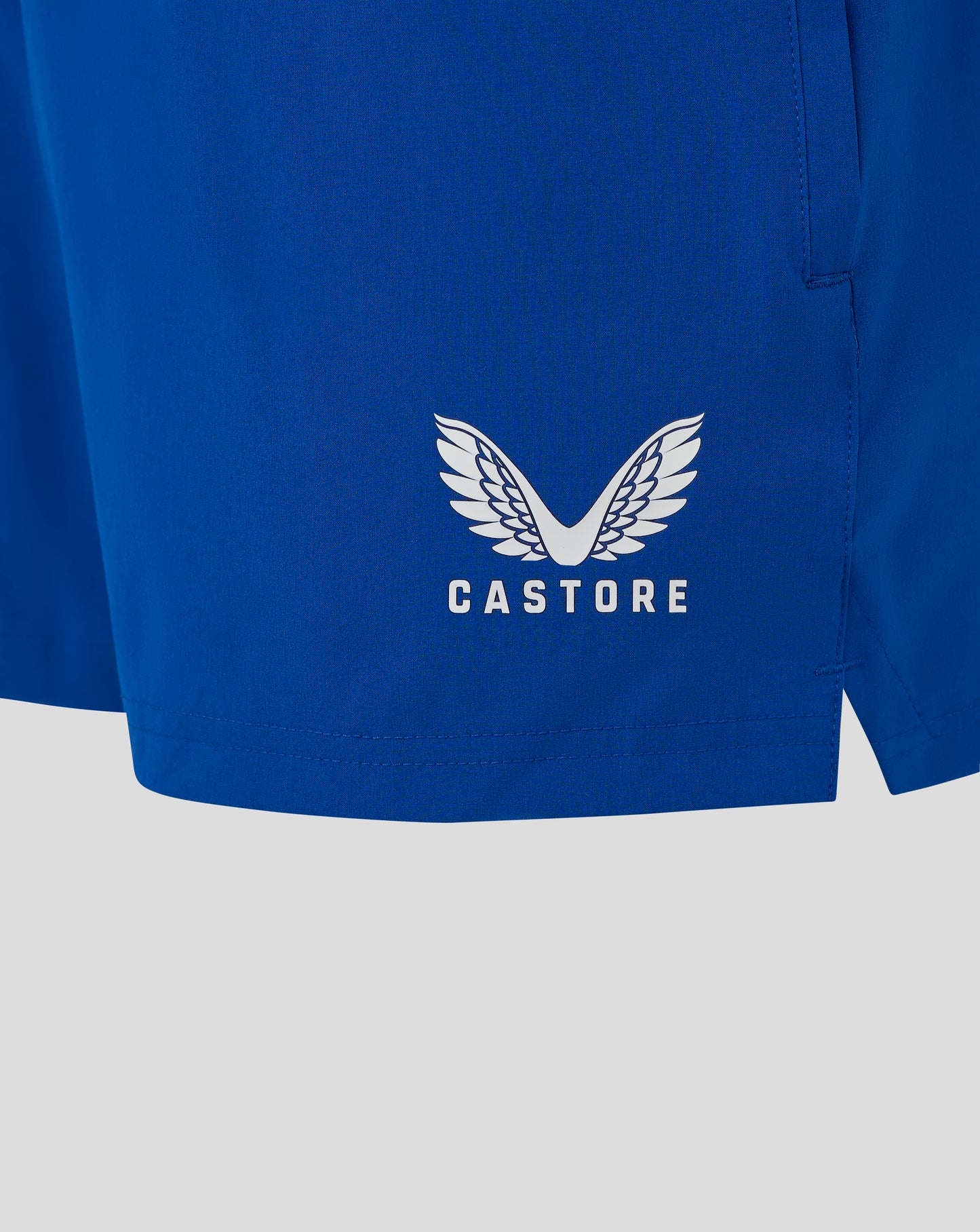 Blue woven training shorts back view showing the white Castore logo on the fabric