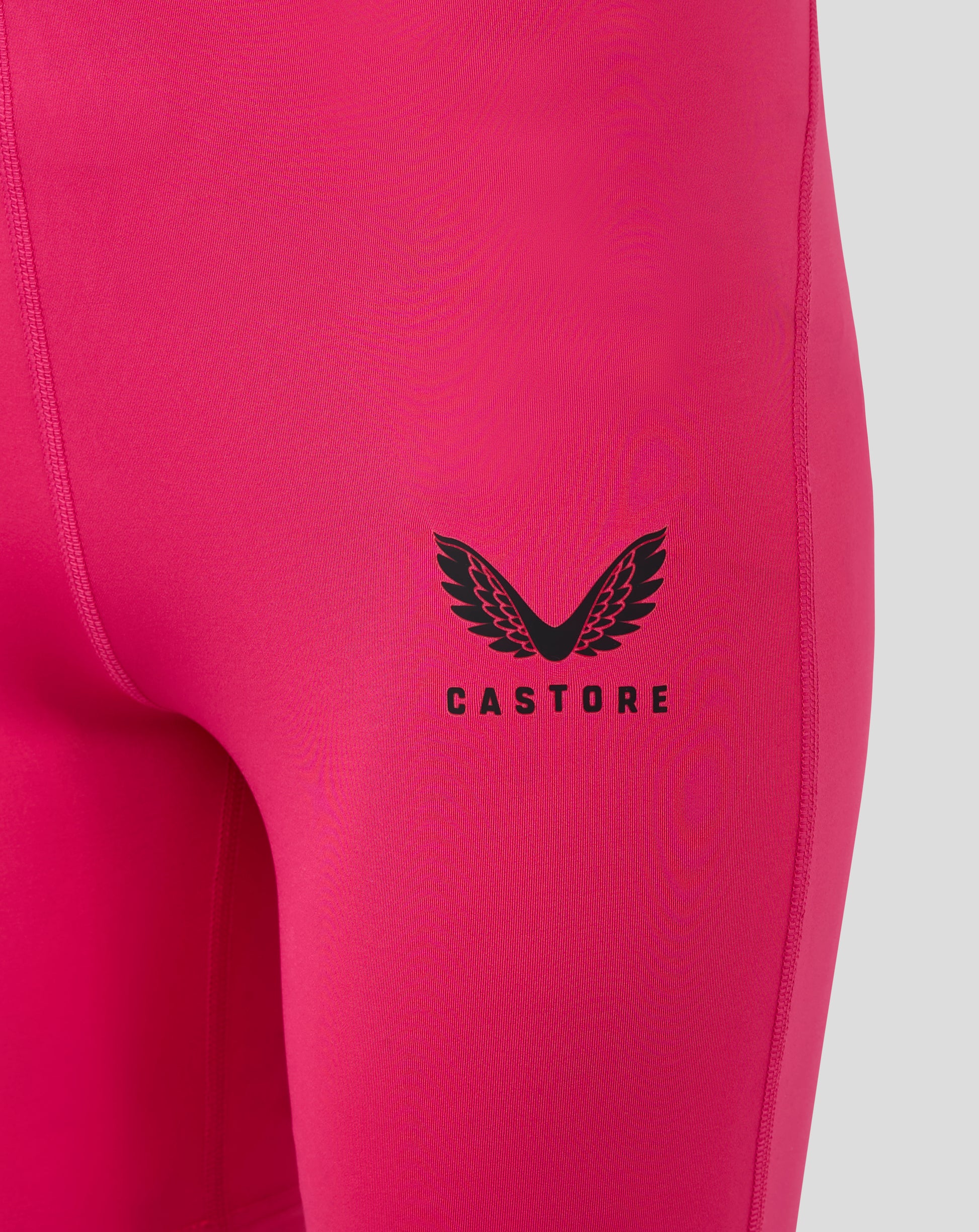 Close-up of Beetroot Purple baselayer fabric with a black winged Castore logo on the leg panel.