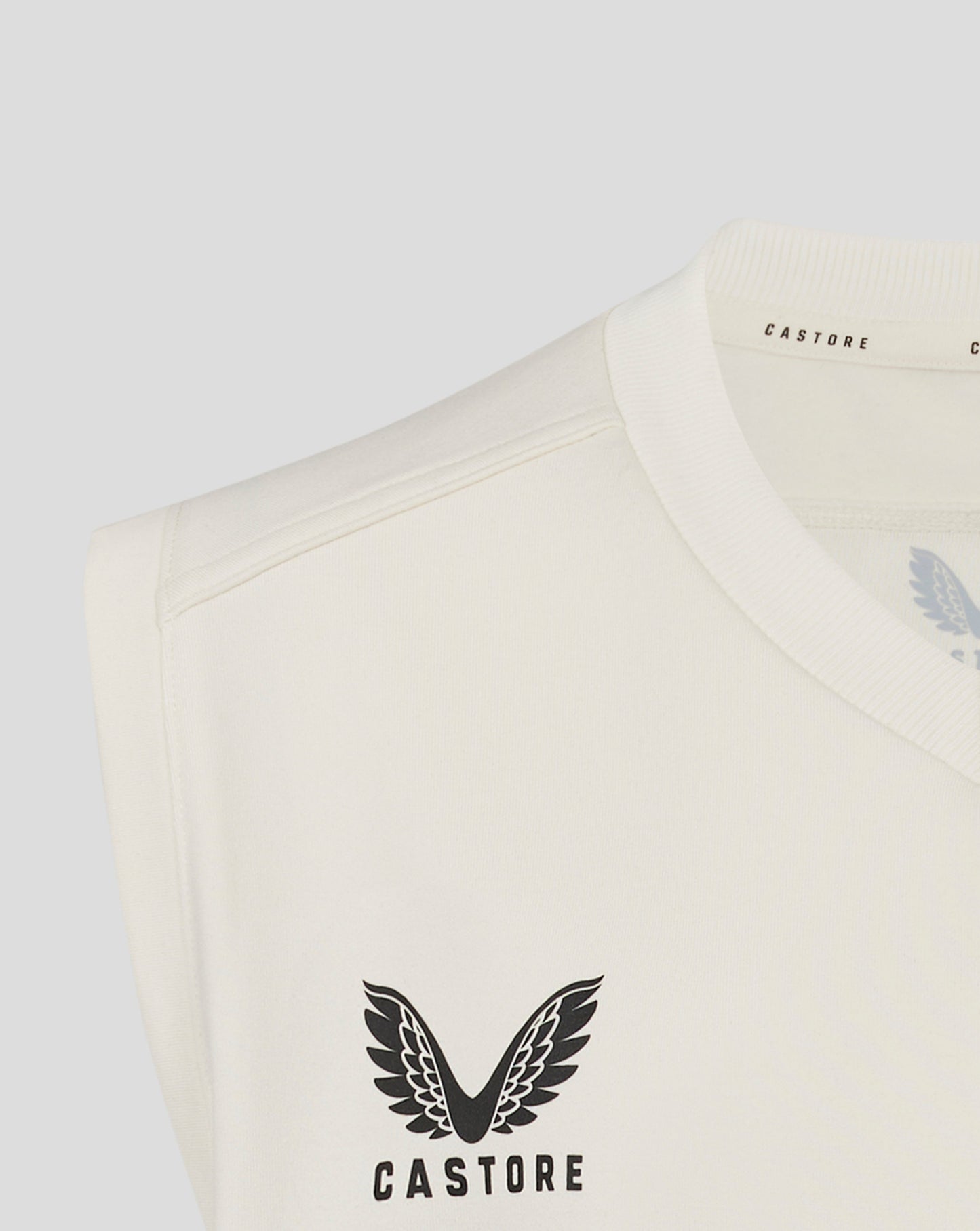Close up of cream sleeveless jumper neckline showing ribbed collar and Castore branding inside
