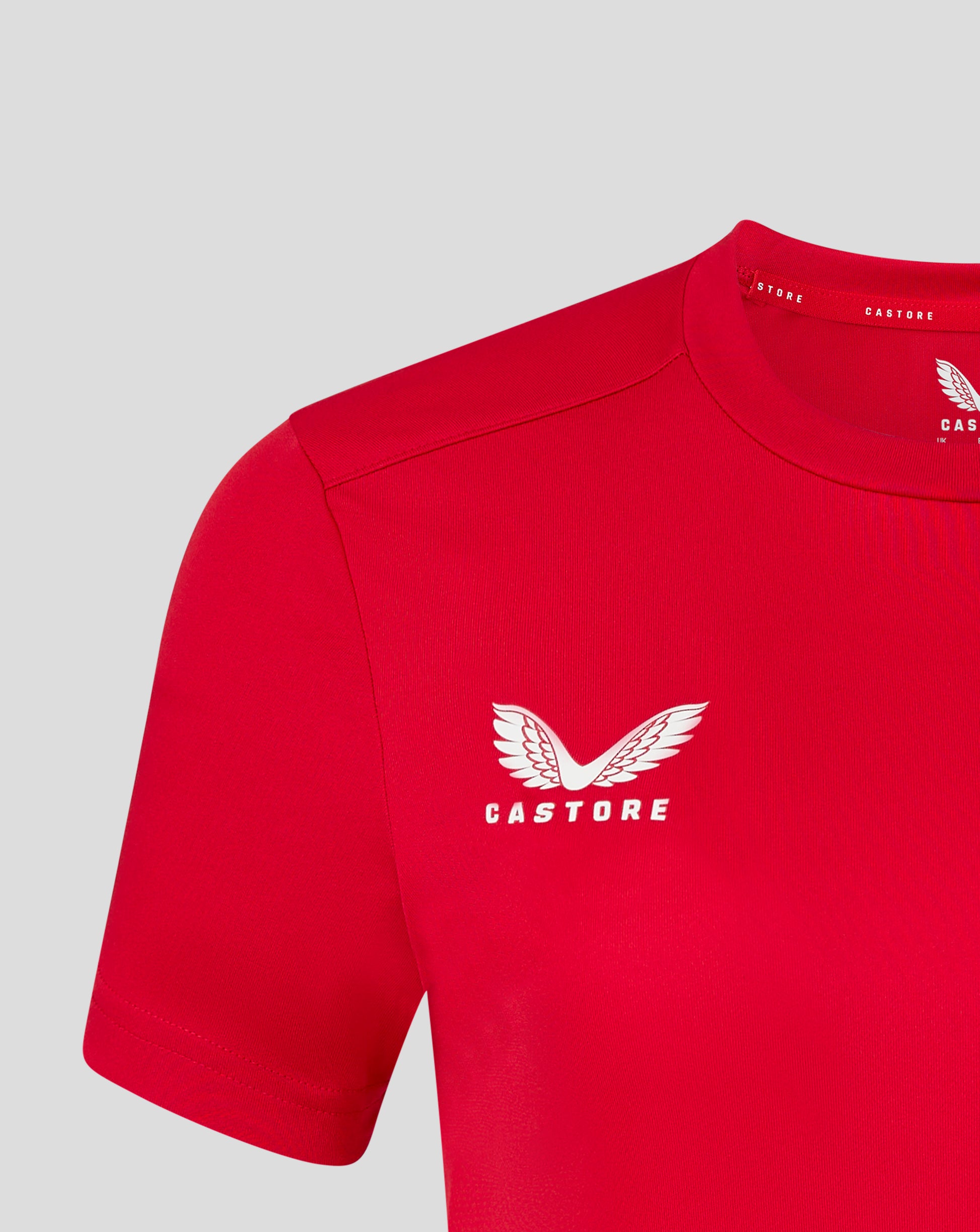 Close up of the red tee at the neckline showing Castore branding along the collar and a partial wing logo