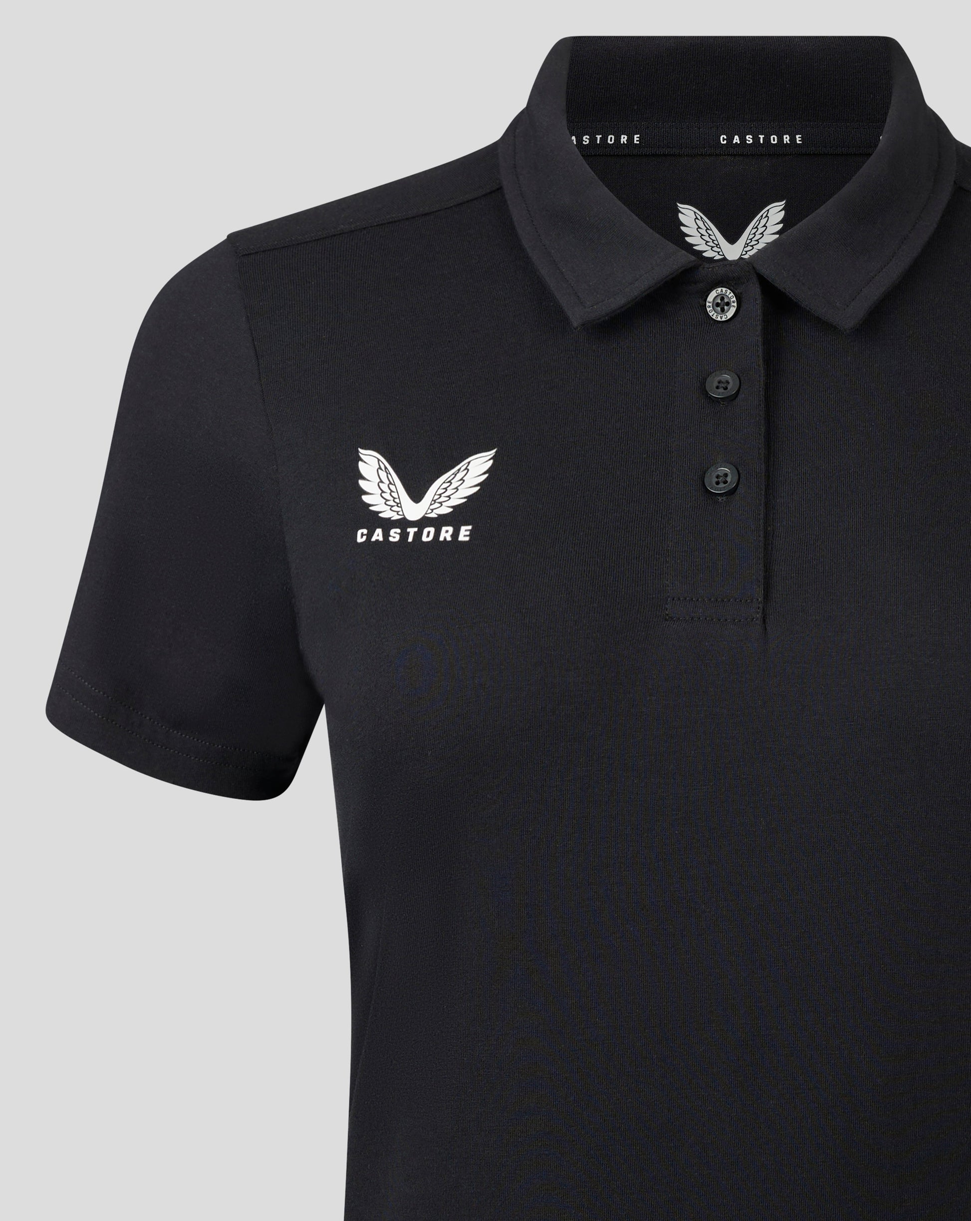 Front close up of black polo showing self fabric collar three button placket and white Castore logo on chest.