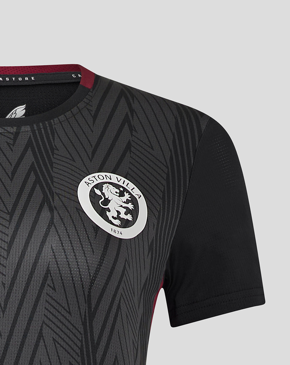 Shoulder and chest view of a dark grey patterned women's Aston Villa staff training general short sleeve shirt with the white club crest.