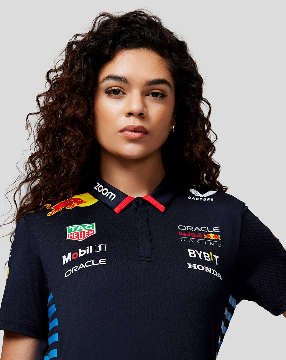 Front view of a woman in navy Night Sky Teamline polo with sponsor logos on the chest