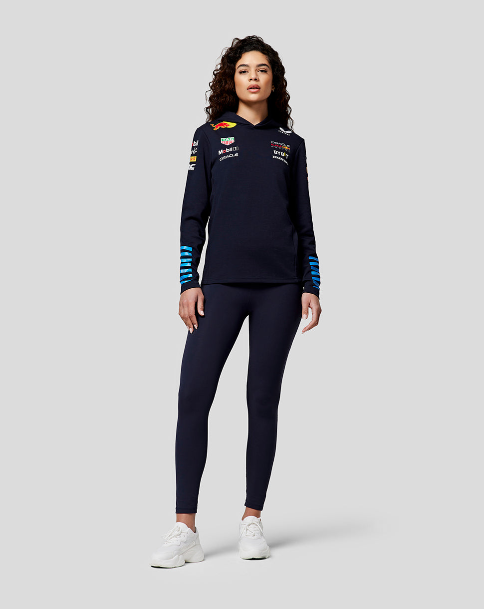 Model in navy Night Sky Teamline Hoodie with blue striped cuffs and chest logos.