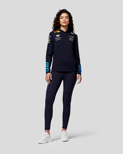 Model in navy Night Sky Teamline Hoodie with blue striped cuffs and chest logos.