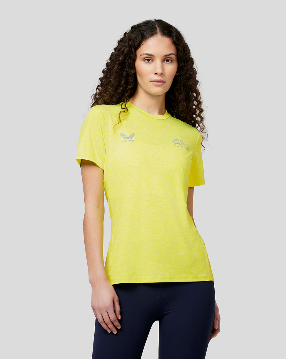Front view of a woman in a bright safety yellow Red Bull Racing Active Dual Brand Tee with small logos on the chest.