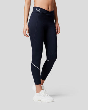 Model wearing navy Night Sky running leggings with reflective piping and a logo on the waistband.