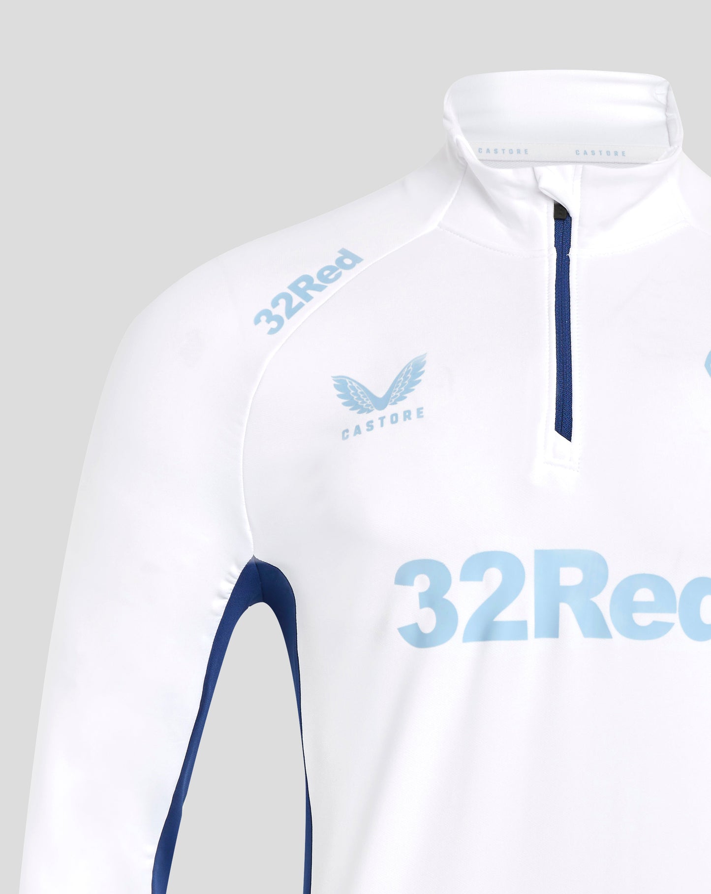 Front close up of white training top showing blue front zipper and light blue club crest on chest