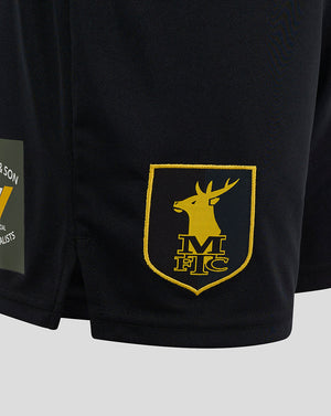 Close-up of Mansfield Third Shorts fabric with a raised yellow crest on the right thigh and Castore branding on the left.