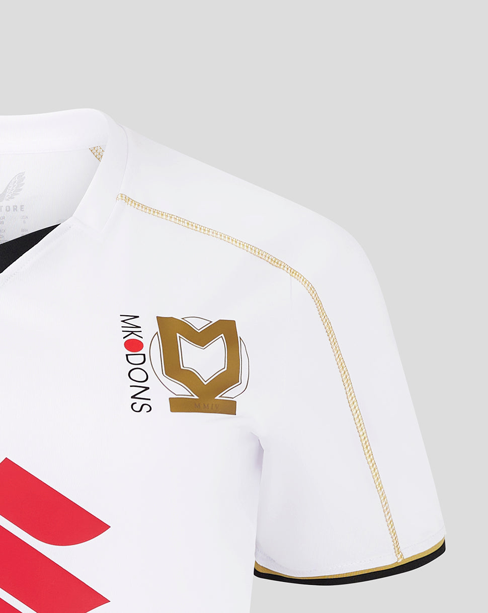 Close-up of a white MK Dons women's home shirt showing crest and gold piping along the shoulder.