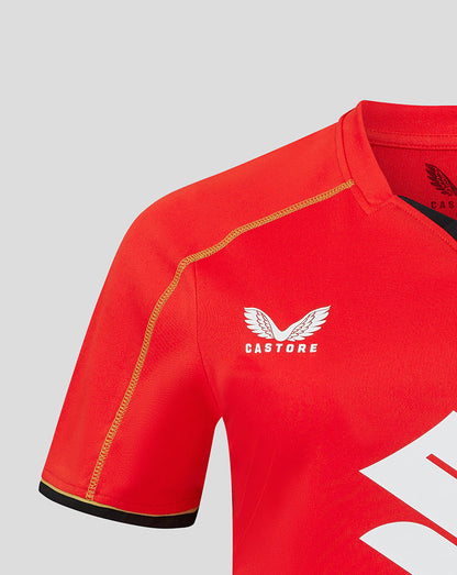 Red Mk Dons away shirt close up showing white Castore logo and gold crest on the chest.