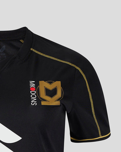 Close up of Mk Dons women's 24/25 third shirt chest showing a gold crest emblem and gold piping on black fabric