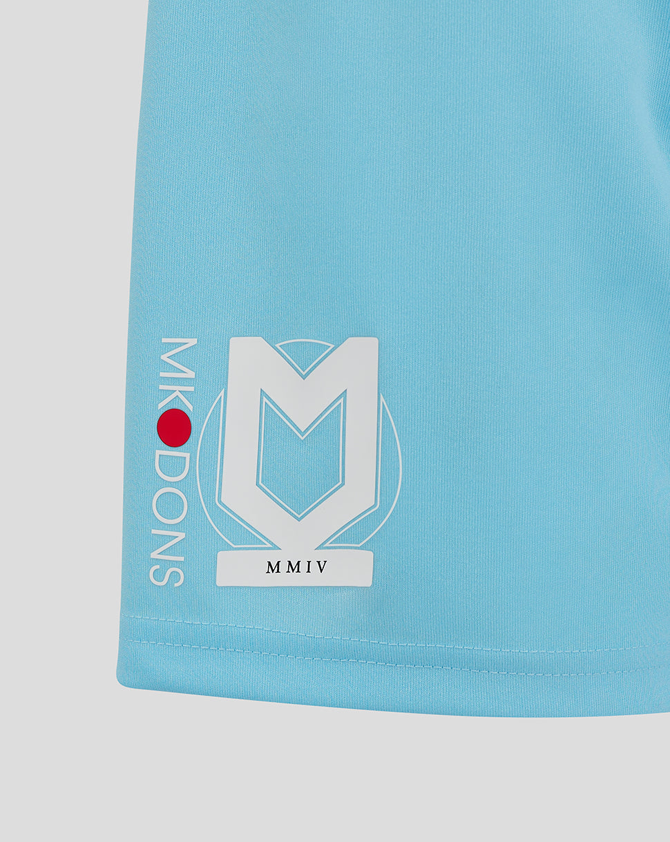 Close up of light blue Mk Dons shorts featuring a large white crest logo on the left leg and vertical Mk Dons text along the side