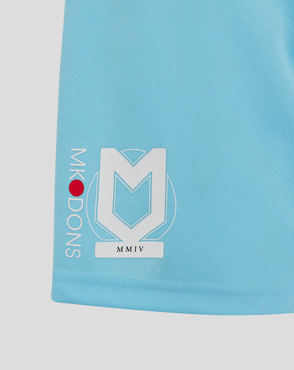Close up of light blue Mk Dons shorts featuring a large white crest logo on the left leg and vertical Mk Dons text along the side