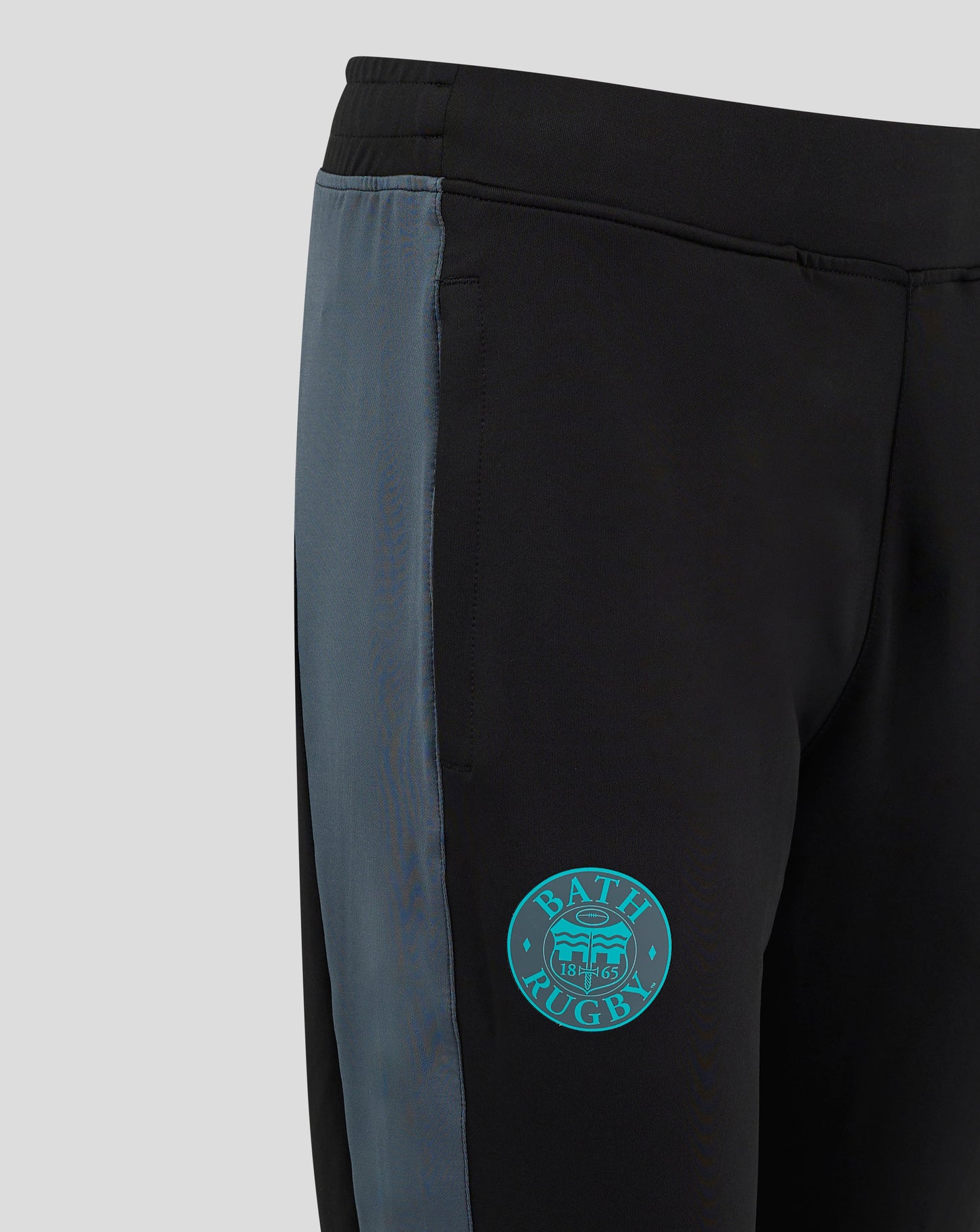 Front view of Bath Rugby training pants in black with teal thigh logos the team crest on left and Castore on right