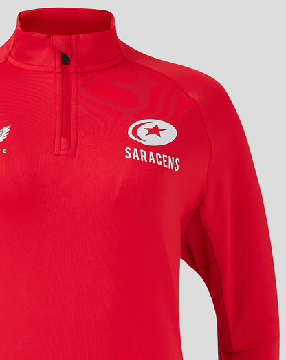 Close-up of red training top chest showing white Saracens crest and Castore emblem