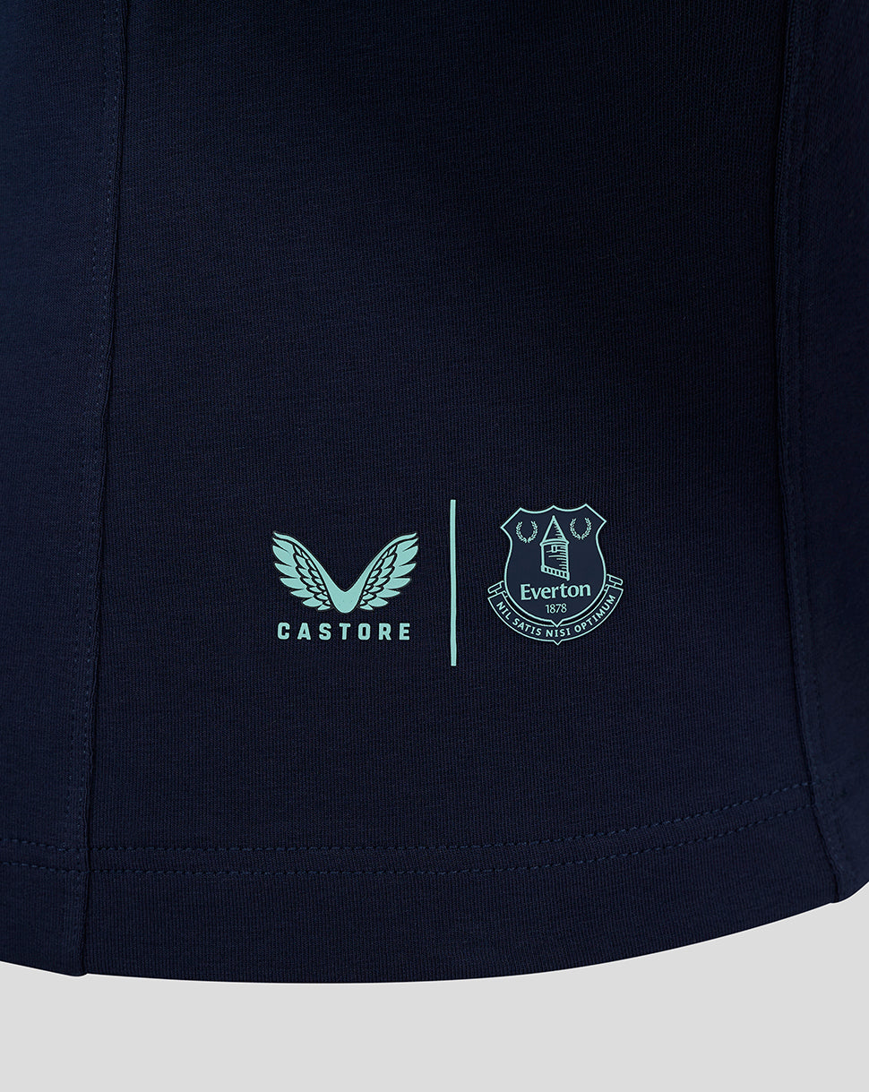 Close up of navy polo hem featuring Castore logo and Everton crest separated by a vertical line.