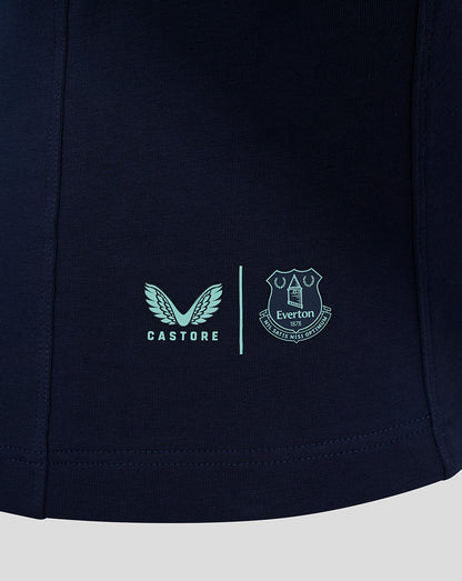 Close up of navy polo hem featuring Castore logo and Everton crest separated by a vertical line.