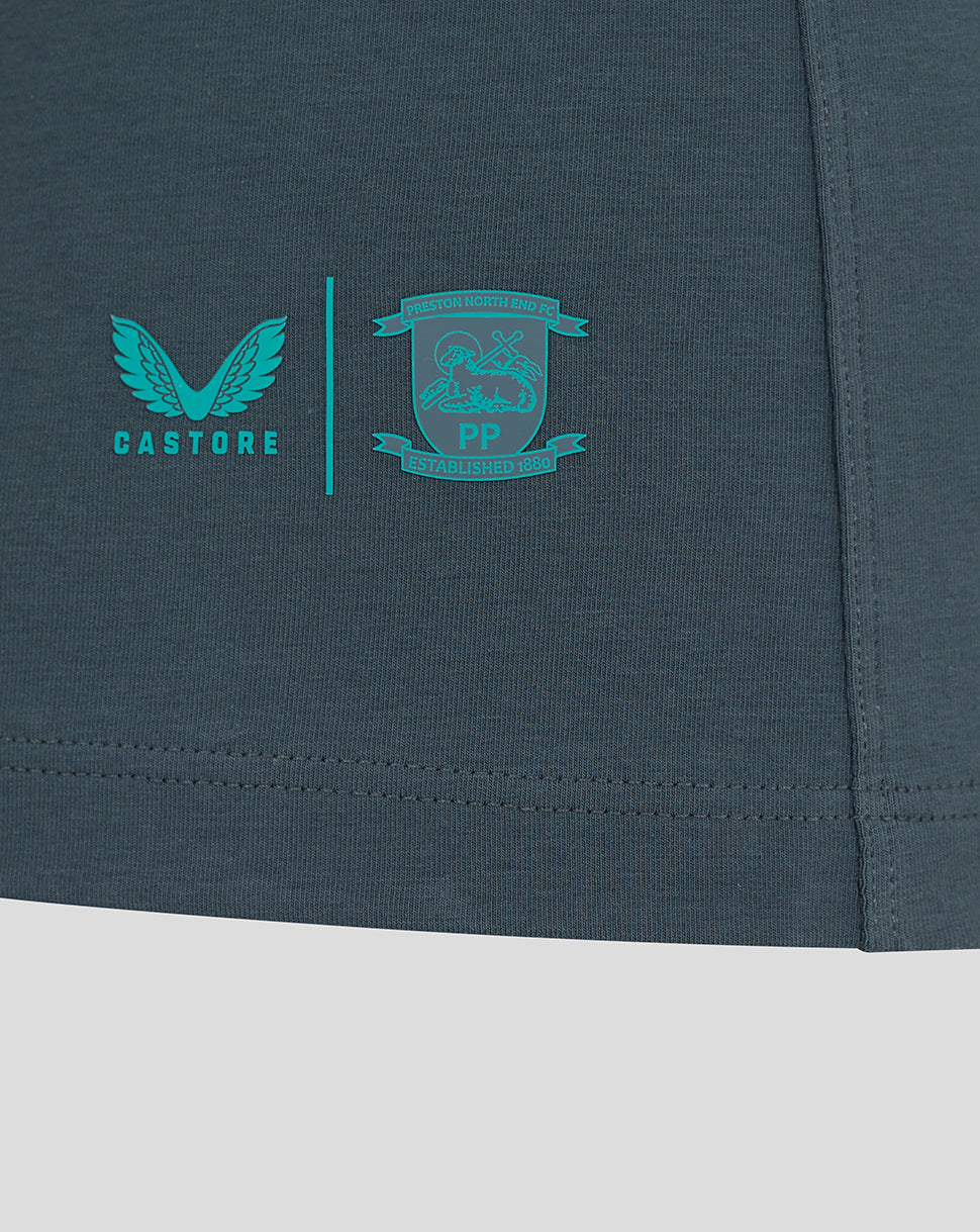 Close up of teal Castore logo and the Preston North End crest near the lower right hem of the polo