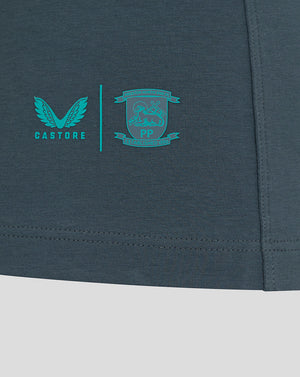 Close up of teal Castore logo and the Preston North End crest near the lower right hem of the polo