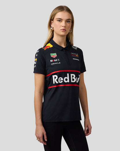 Front view of a female model wearing a night sky navy Red Bull Racing polo with a bold chest logo and sponsor patches