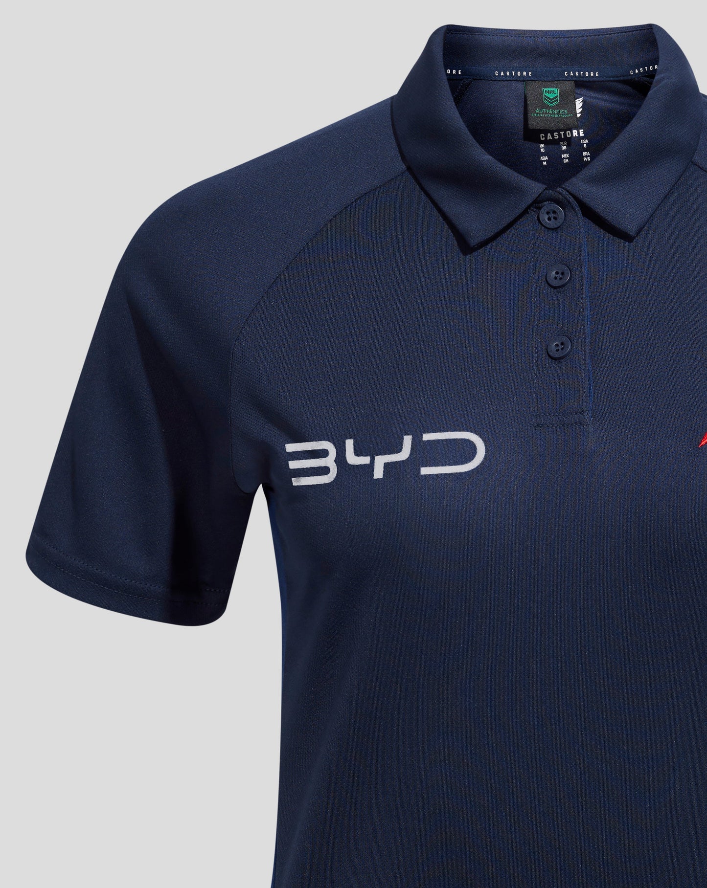 Collar close up of navy polo with a three button placket and Castore branding visible on the neck tape.
