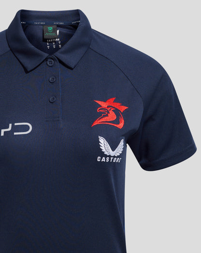 Chest area of navy polo showing a red rooster crest with white wings and Castore branding inside the collar.