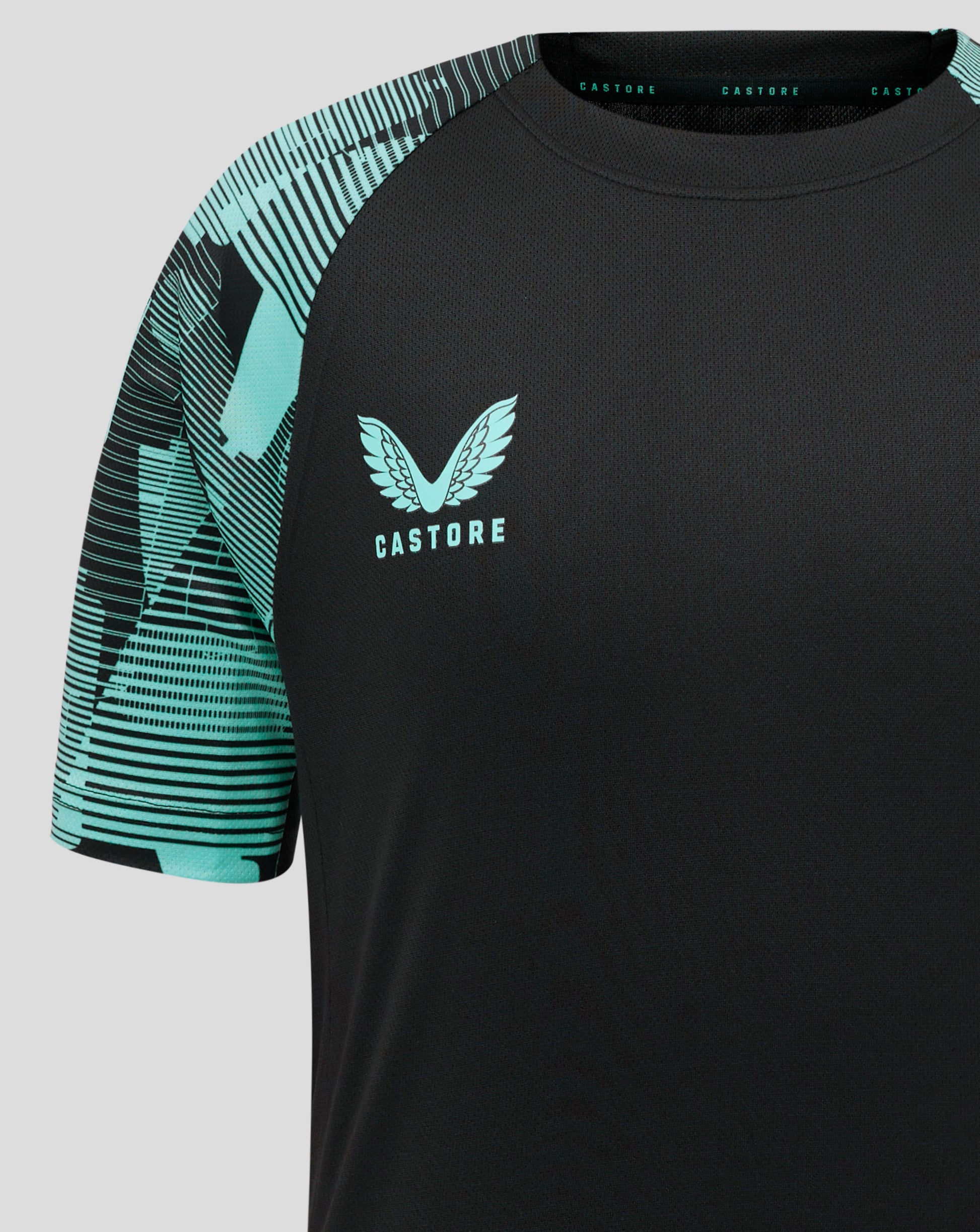 Close up of teal patterned sleeve with Castore branding along the collar and partial front crest on the black junior England shirt.
